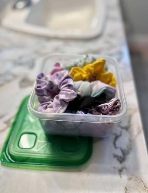 You can use plastic food containers to hold your scrunchies. They make a convenient scrunchie holder.