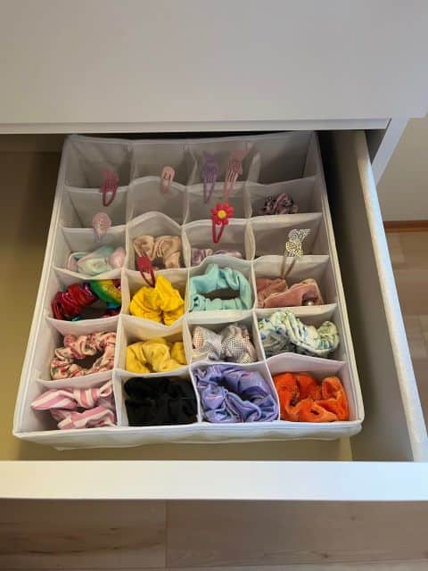 Drawer organizer holding scrunchies in the compartments.