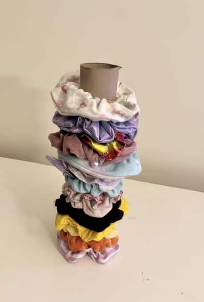 Storing scrunchies on an empty paper towel tube. Then place it on your bathroom counter