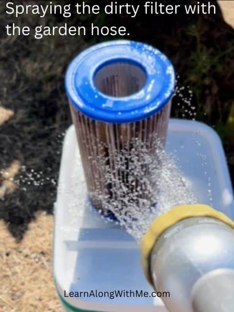 Spray the dirty pool filter with a garden hose to clean it